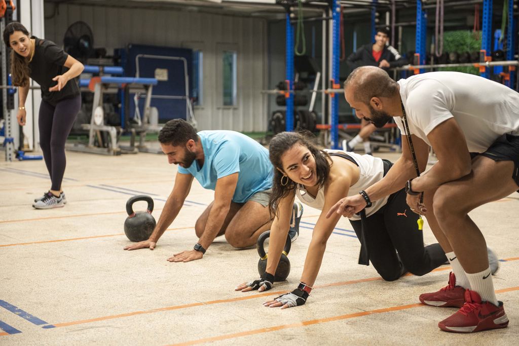 A coach guiding members through a kettlebell drill